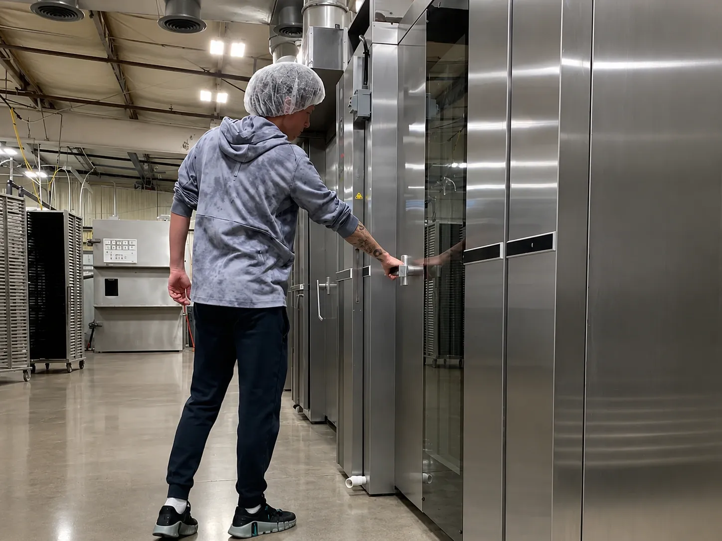 An operator opening a freeze-dryer door on the production floor.